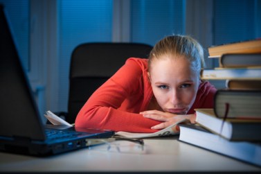 young  bored female college student studying poorly at late even
